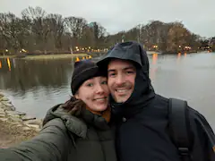 Paar macht Selfie vor einem See an einem kühlen, bewölkten Tag.