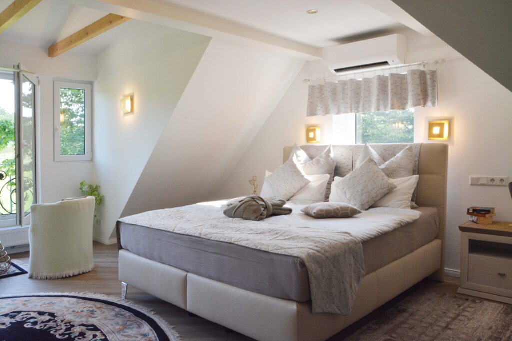 Helles Schlafzimmer mit großem Bett und elegantem Lichtdesign unter Dachschrägen.