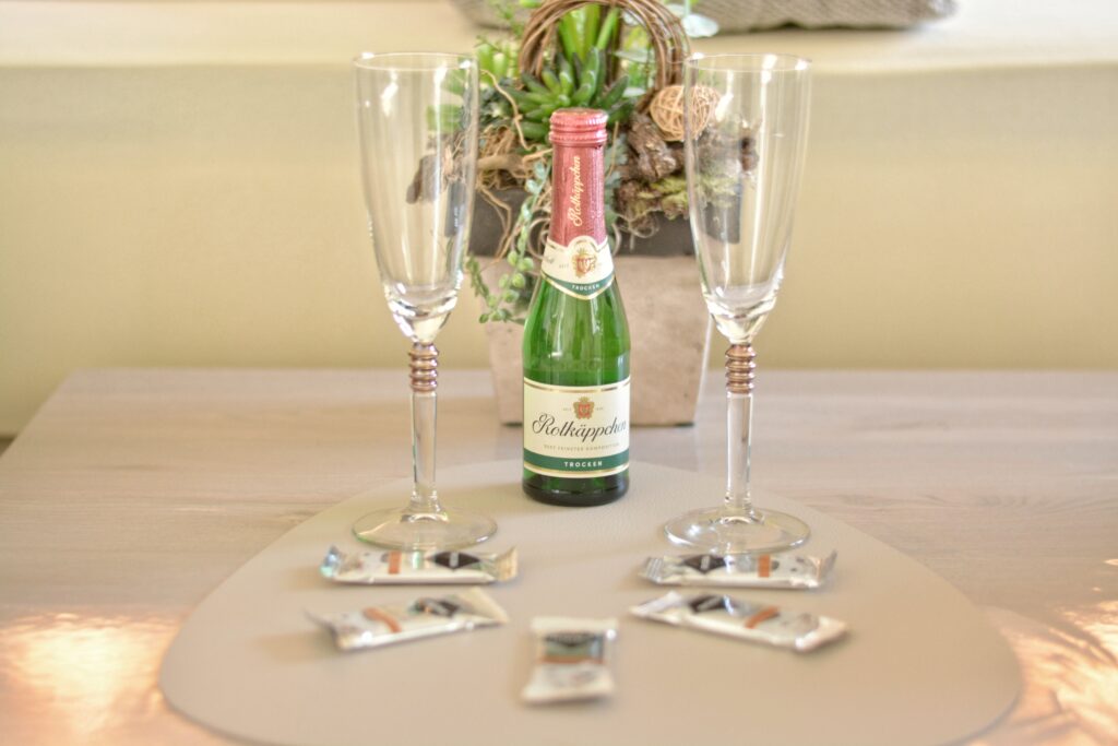 Sektflasche mit zwei Gläsern auf einem Tisch arrangiert.